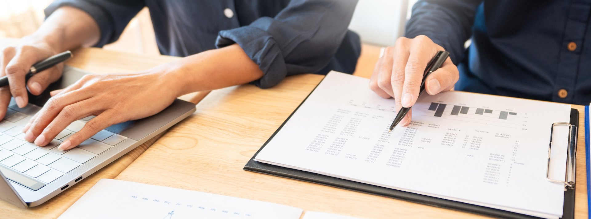 Hands on keyboard and another person writing on budget