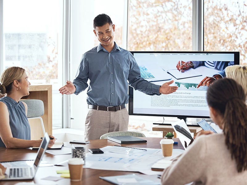 A businessperson giving a presentation to a conference room full of peers