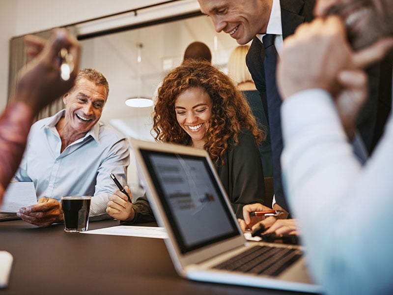 Businesspeople laughing together during a boardroom meeting