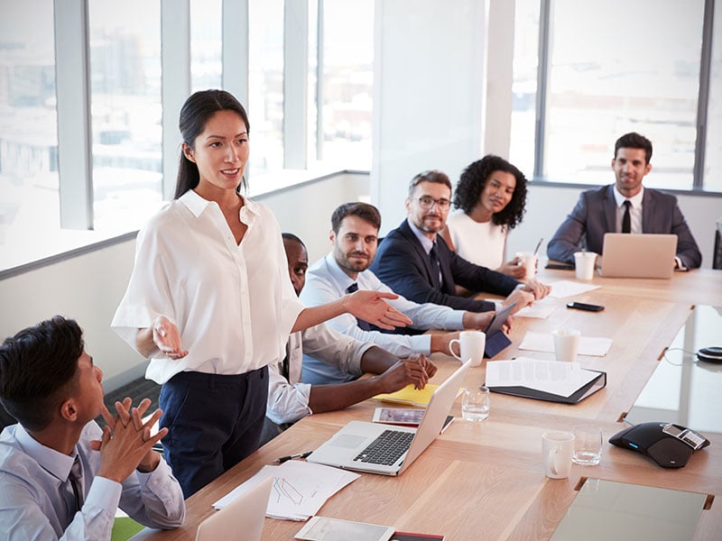 A businessperson presenting to a conference room full of colleagues