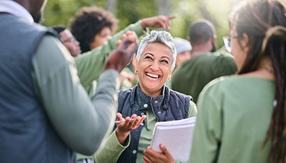 Community service worker holding notebook and interacting with other workers