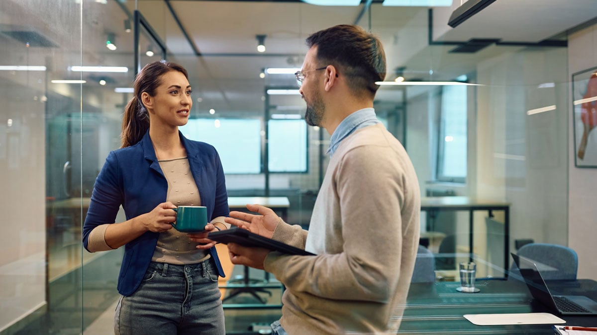 two coworkers chatting in an office halloway between meetings