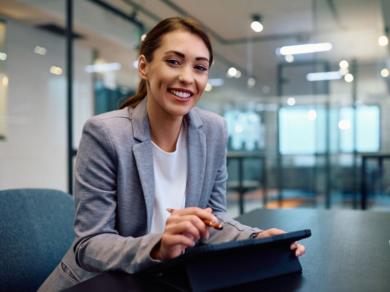 female professional smiling while using tablet in conference room