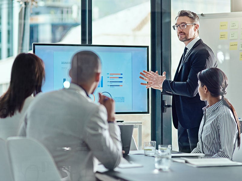 A manager talking about strategy to a conference room of colleagues