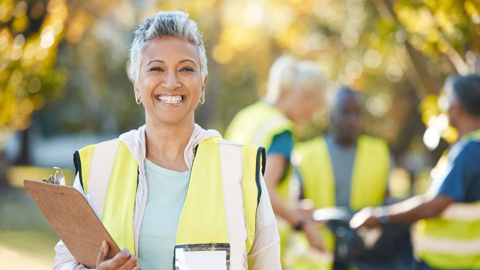 a community worker in a high-visibility vest holding a clipboard