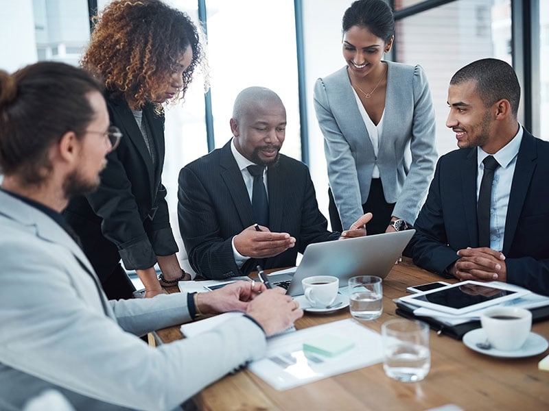 Professionals gathered around a laptop in a conference room