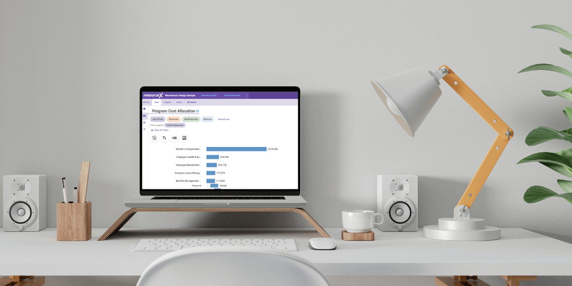 A laptop perched on a stand on a modern desk. The ResourceX platform is opened up on the laptop’s screen.