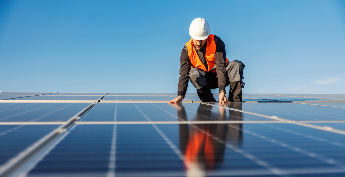 A handyman installing solar panels on the rooftop